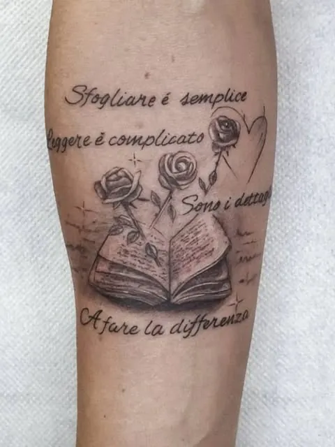 Tatuaggio su avambraccio con libro, rose e scritte